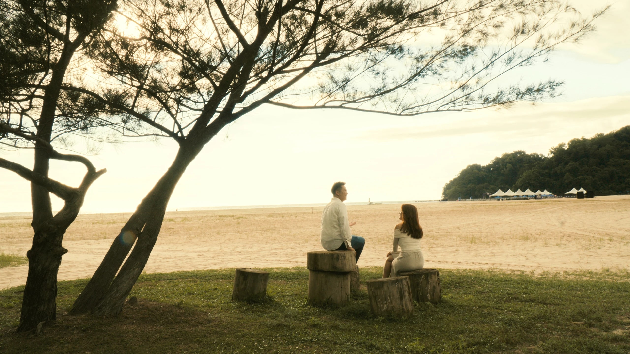Ian and Phy sitting together beside the wide beach at Rasa Ria